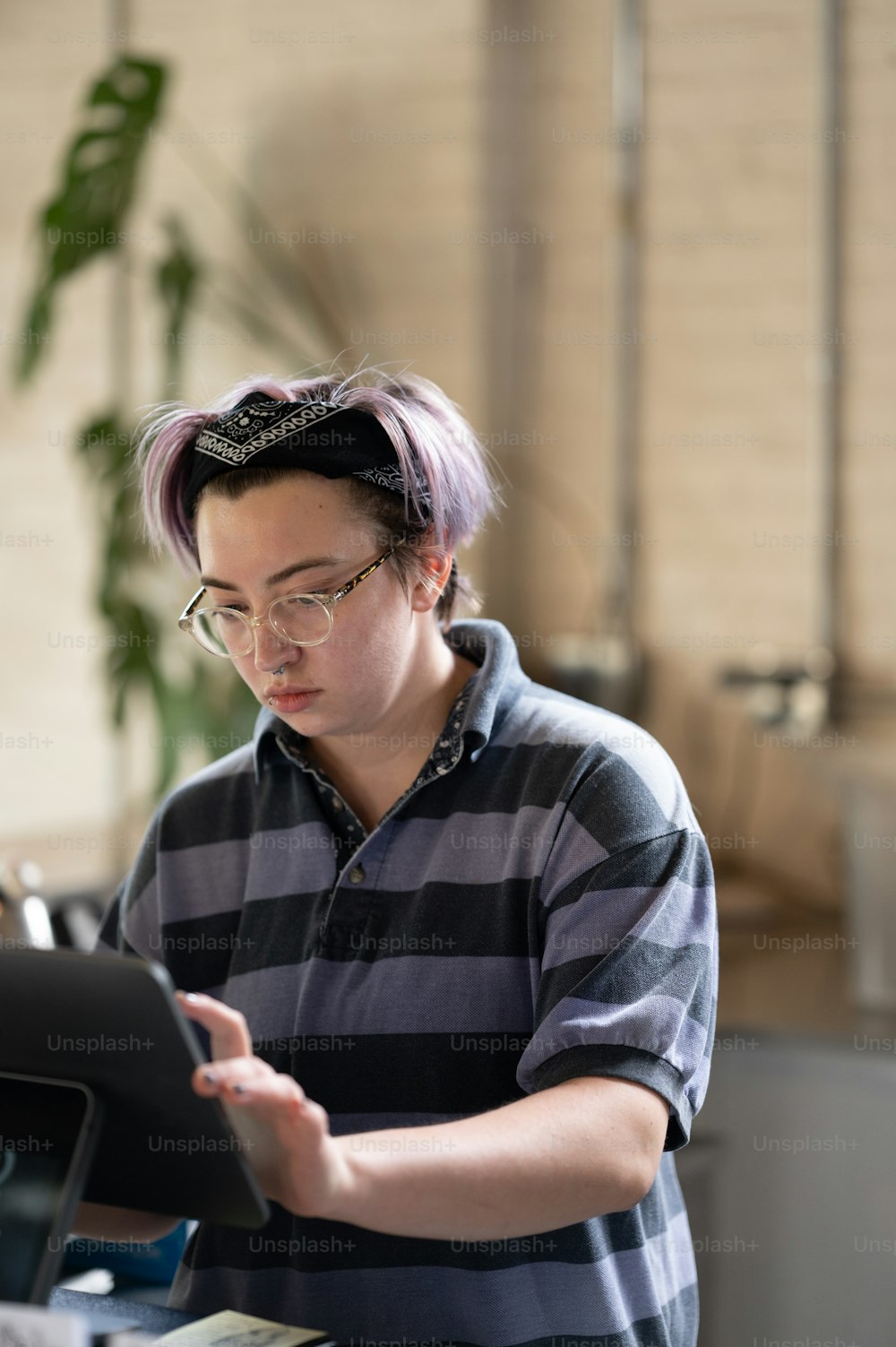 a woman with purple hair is looking at a tablet