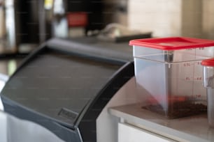 a plastic container with a measuring cup on top of it