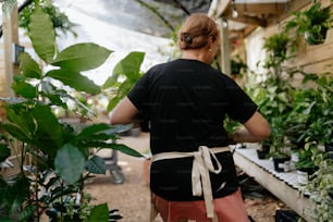 a woman working in a greenhouse with lots of plants