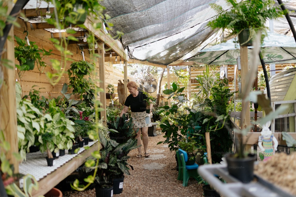 a woman standing inside of a greenhouse filled with lots of plants