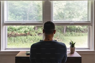 a man sitting at a desk looking out a window
