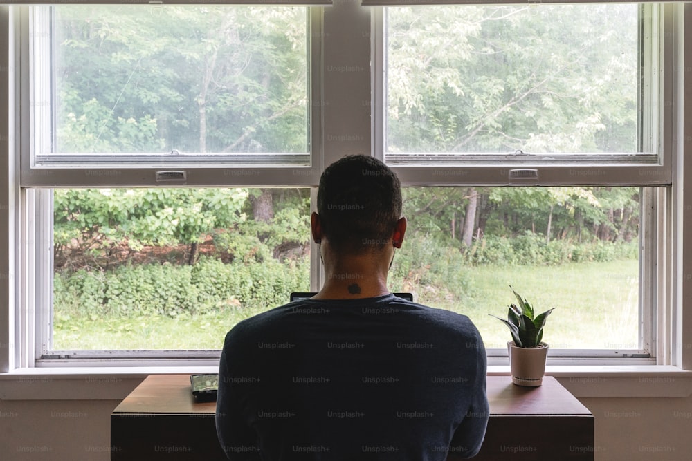 a man sitting at a desk looking out a window