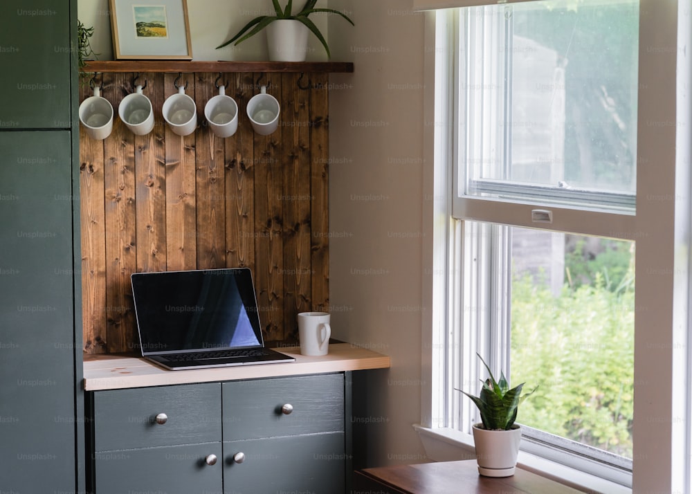 Ein Laptop, der auf einer Theke neben einem Fenster sitzt