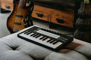um teclado sentado em cima de um sofá ao lado de uma guitarra