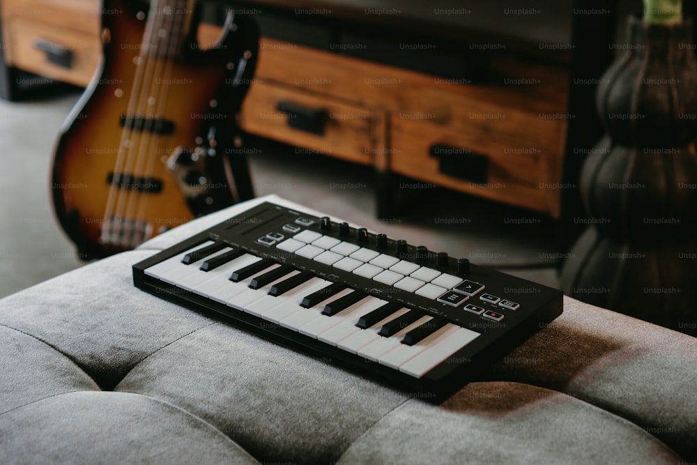 a keyboard sitting on top of a couch next to a guitar