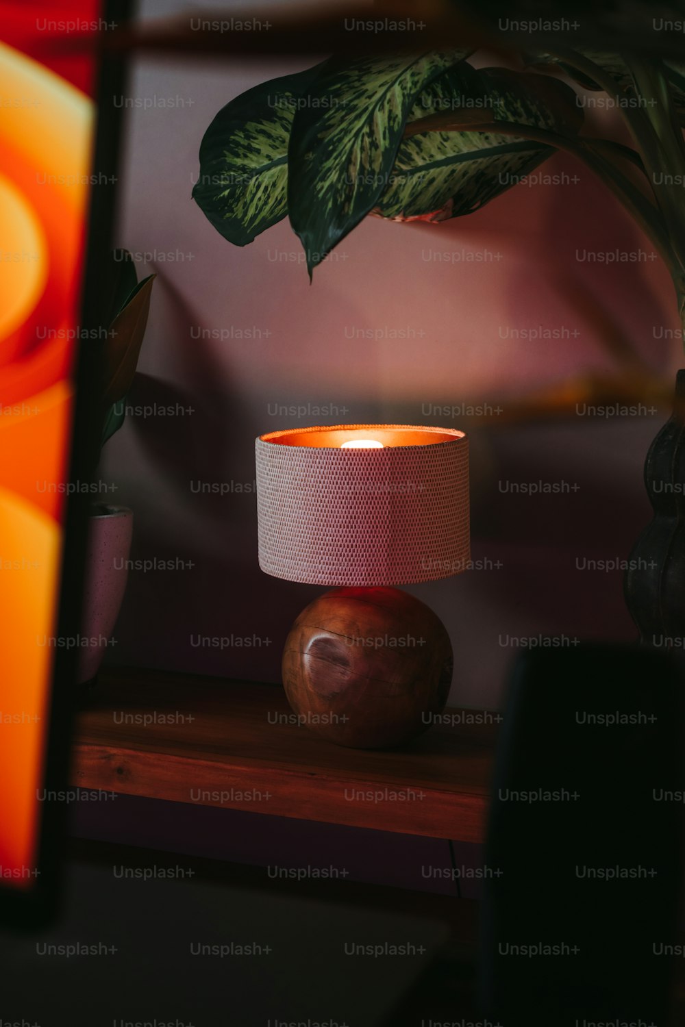 uma lâmpada que está sobre uma mesa ao lado de um vaso de planta