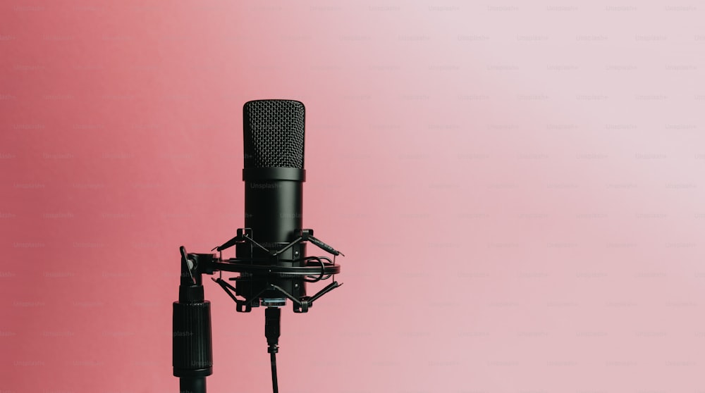 Un micrófono negro sobre fondo rosa