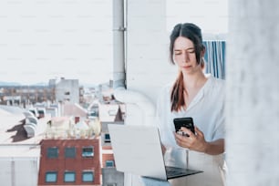 a woman sitting on a ledge looking at her cell phone