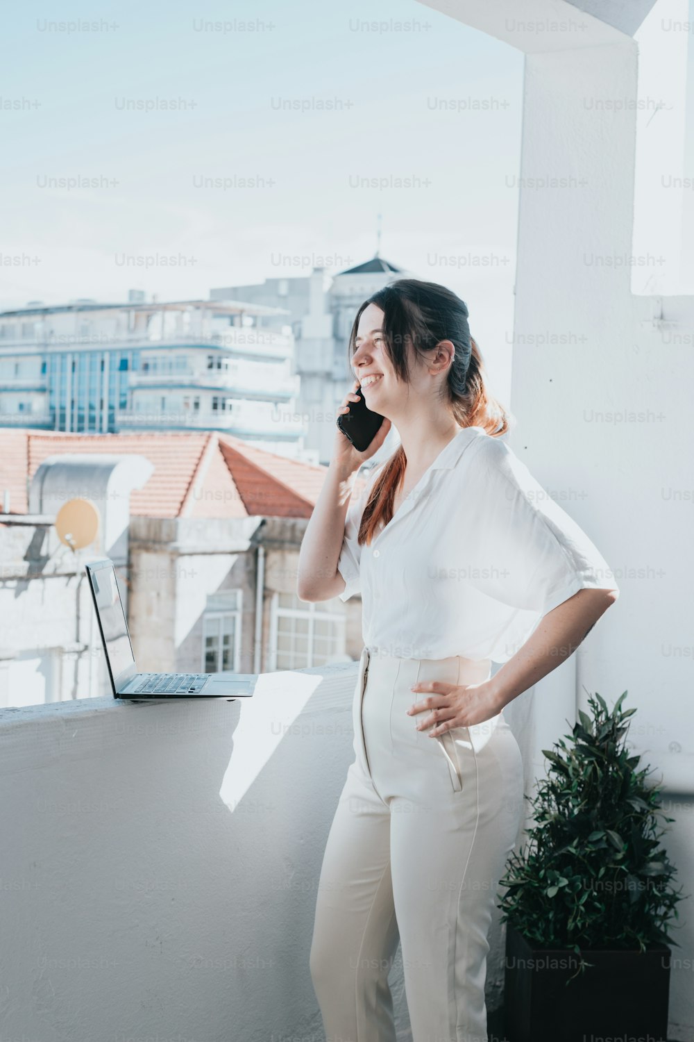 a woman standing on a balcony talking on a cell phone