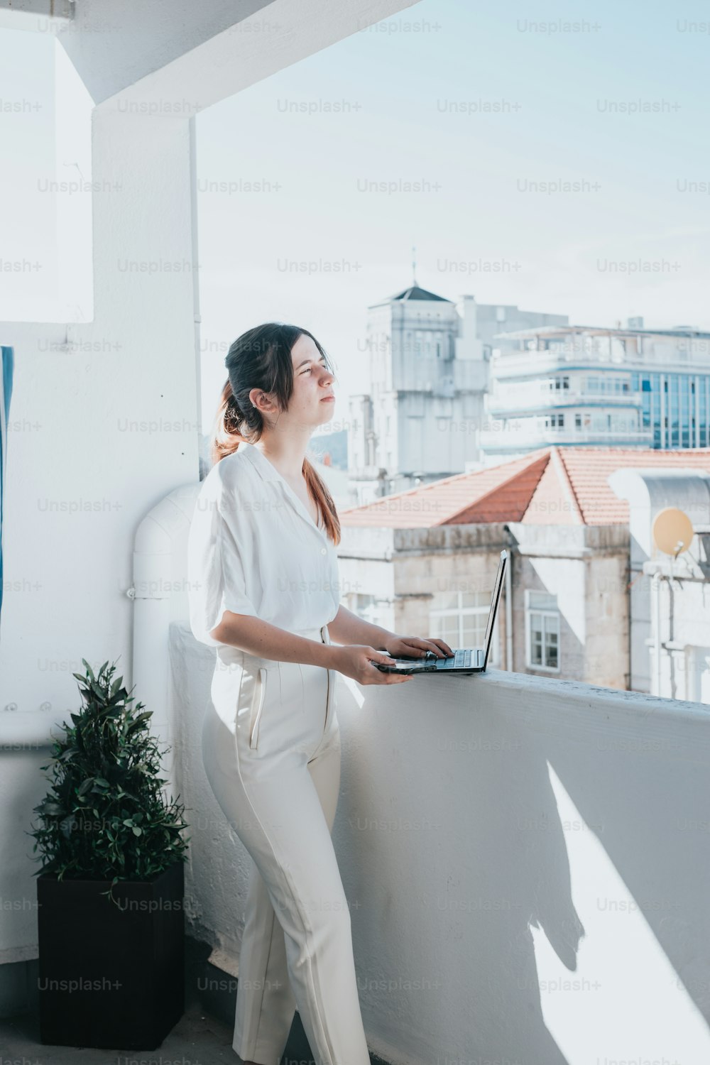 a woman standing on a balcony holding a laptop