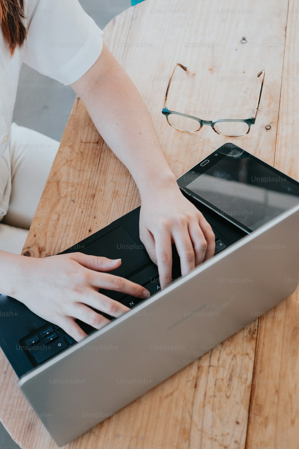 a person typing on a laptop on a wooden table