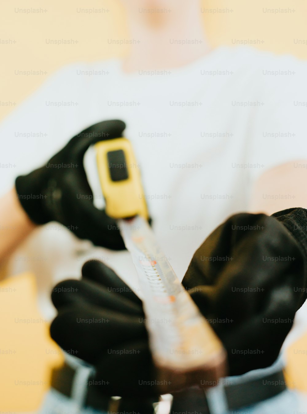 a person wearing black gloves holding a yellow and black device