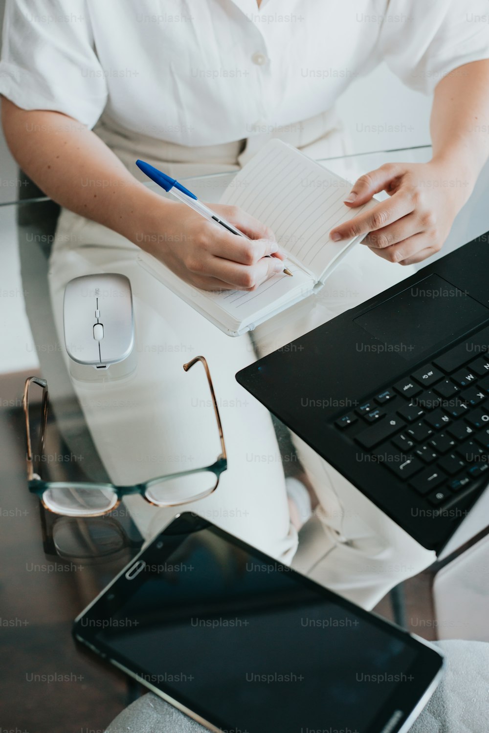 une personne assise à un bureau avec un ordinateur portable et une souris