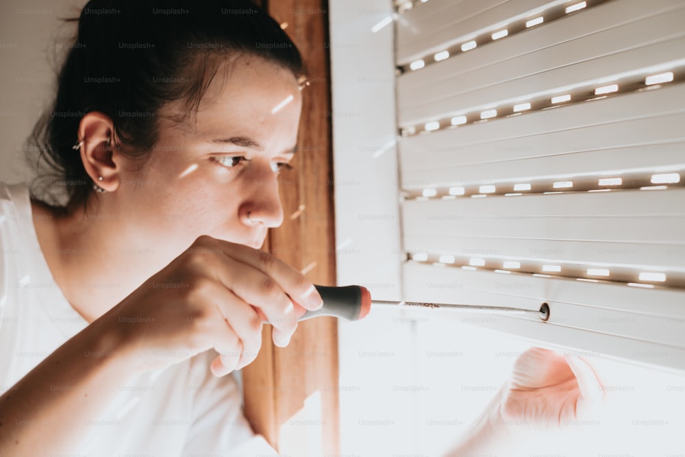 a woman looking out a window with a knife in her hand