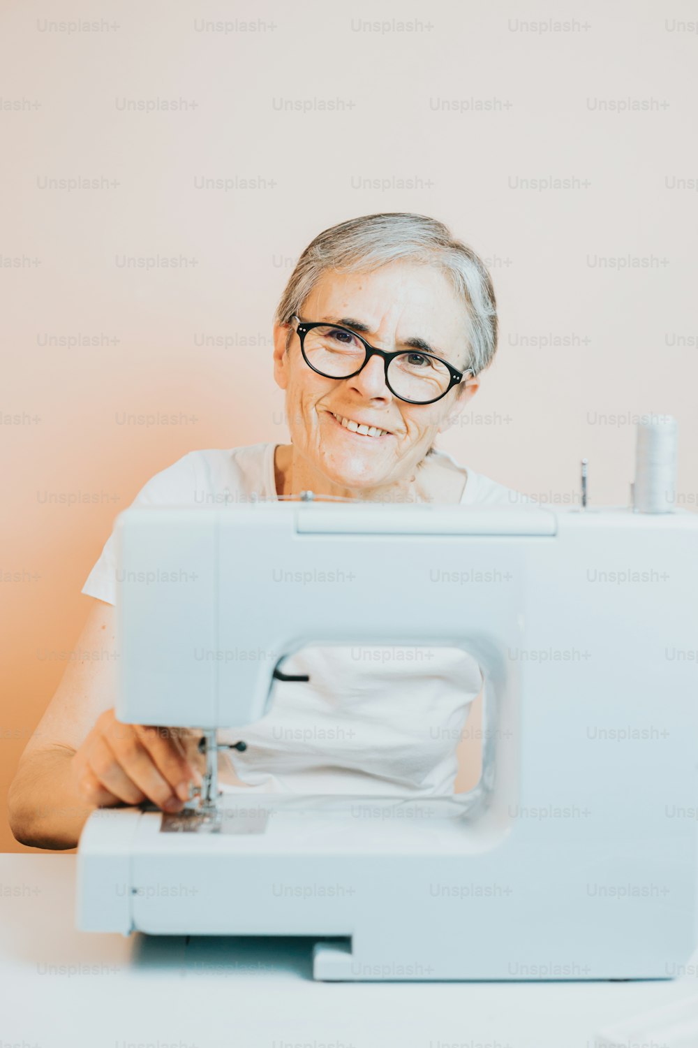 an older woman is smiling while using a sewing machine