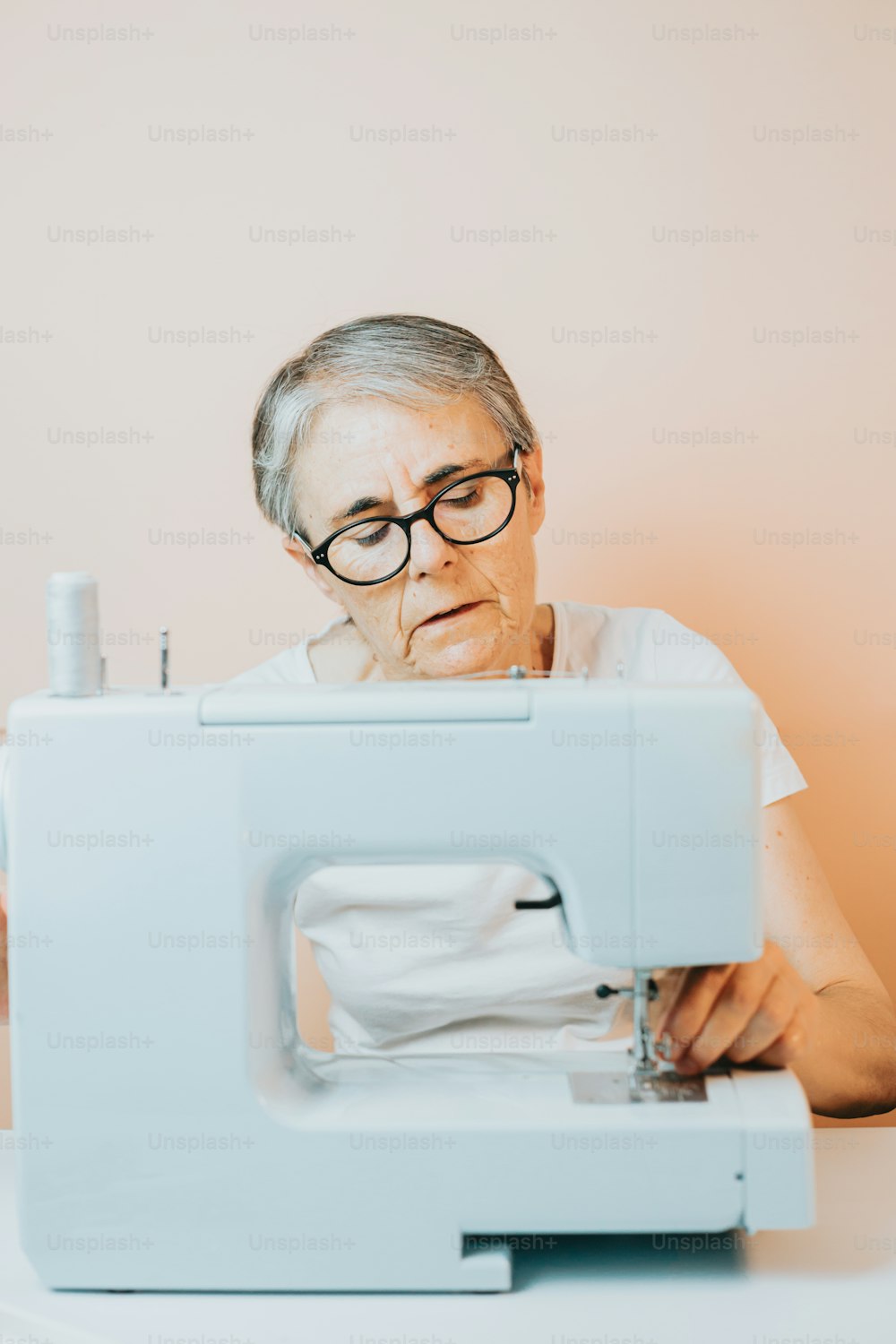 Uma idosa está usando uma máquina de costura