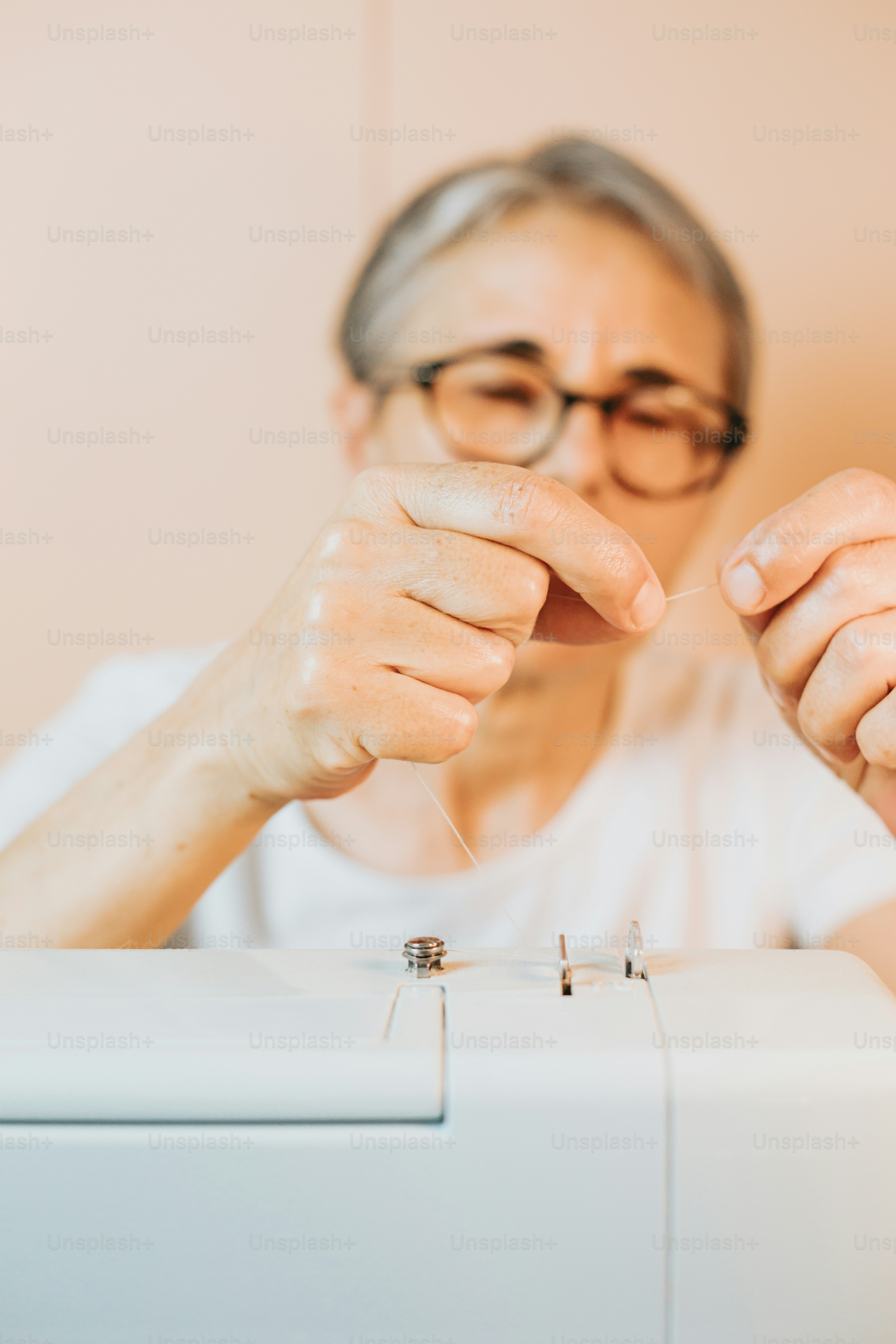 eine frau, die ein stück faden vor einer nähmaschine hält