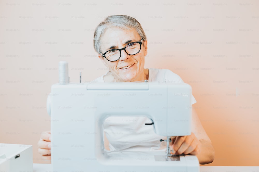 Uma mulher mais velha está sorrindo enquanto usa uma máquina de costura
