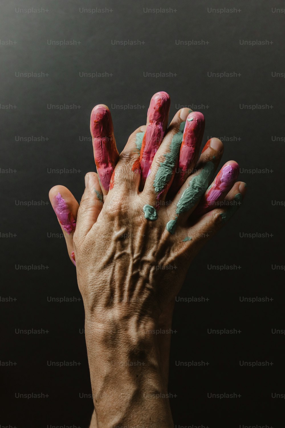 a person's hand with pink and green paint on it
