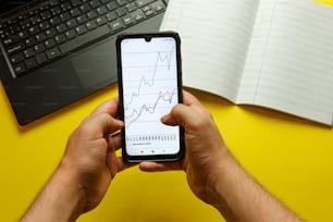 a man holding a cell phone in front of a laptop