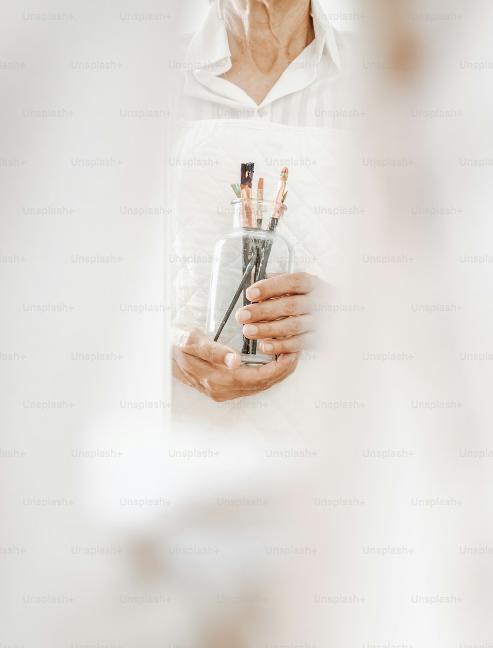 a woman holding a vase with a lot of pens in it