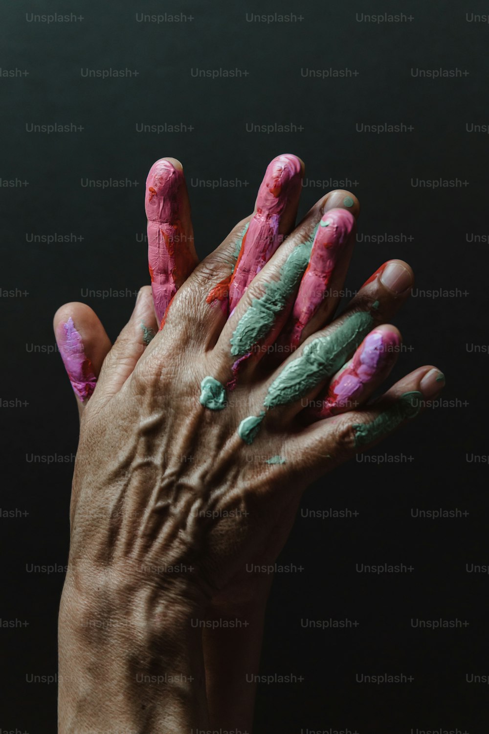 a person's hand with pink and green paint on it