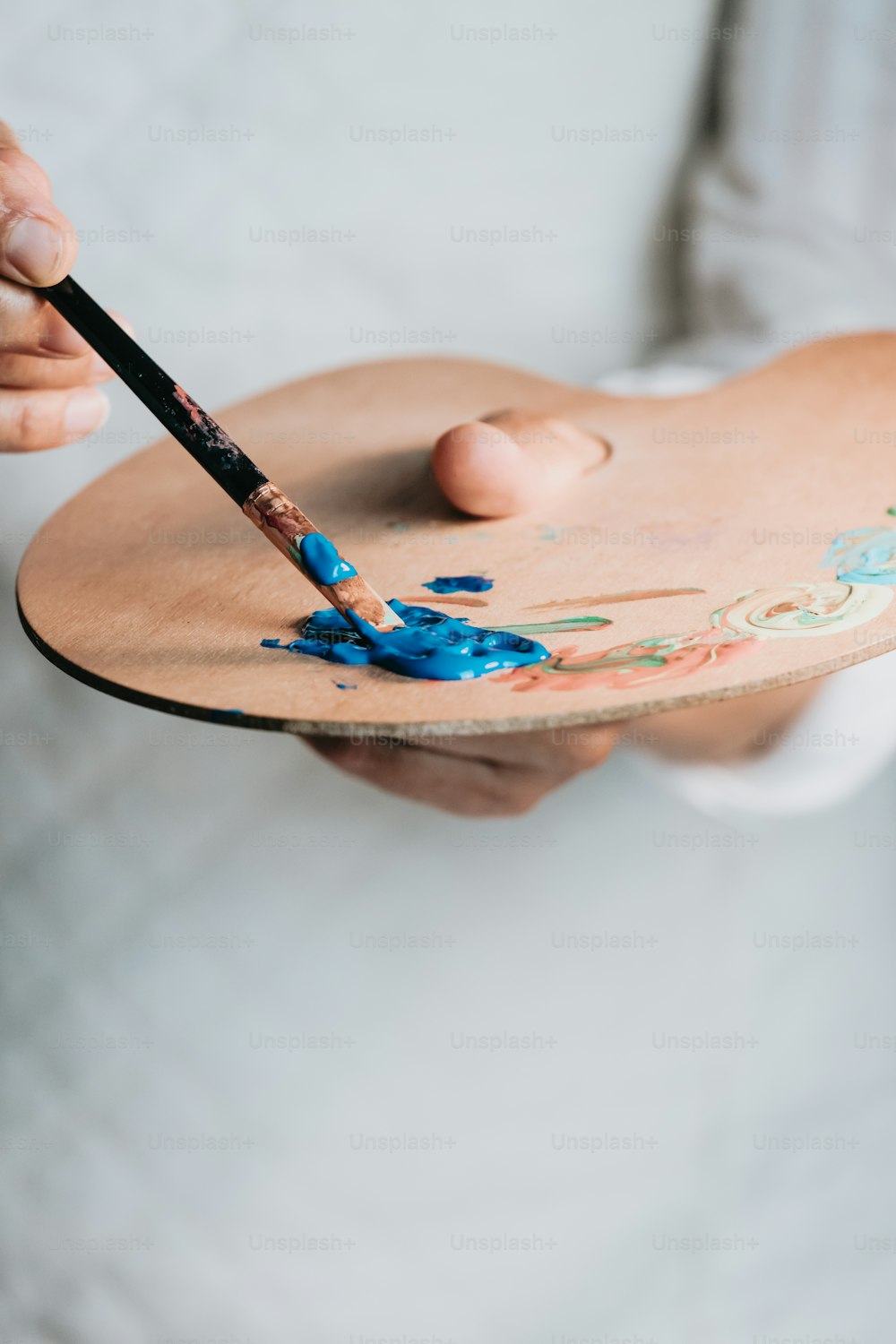 a person holding a wooden plate with paint on it