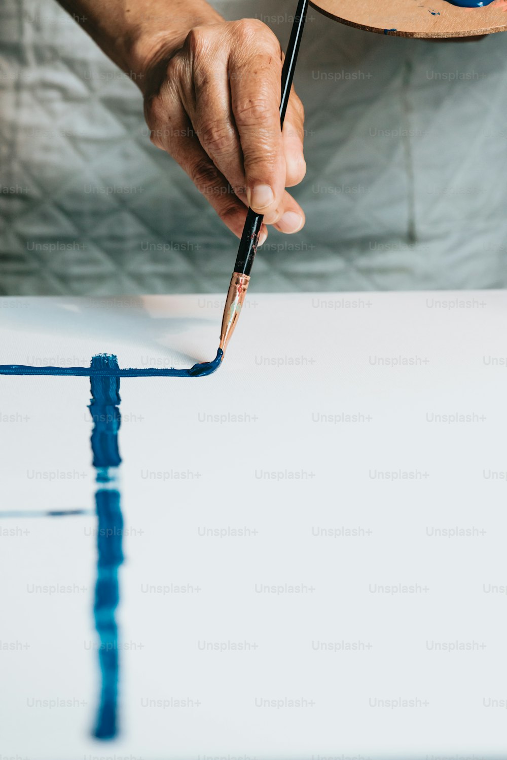 a person holding a paintbrush and painting a piece of paper