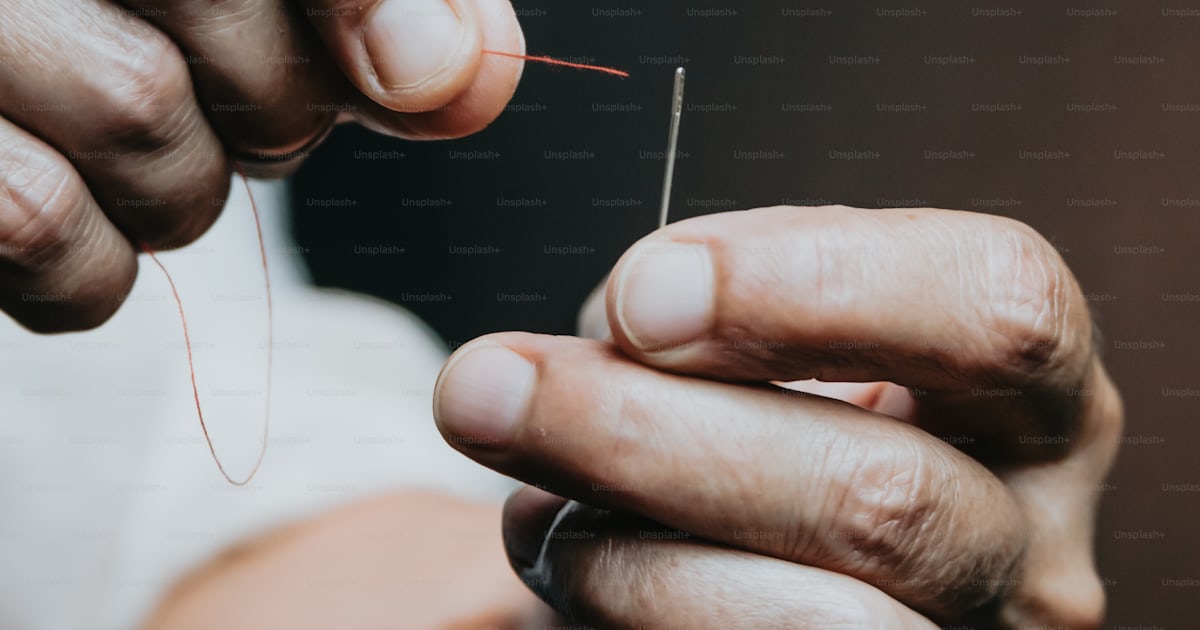 A person holding a thread in their hands photo – Needle Image on Unsplash