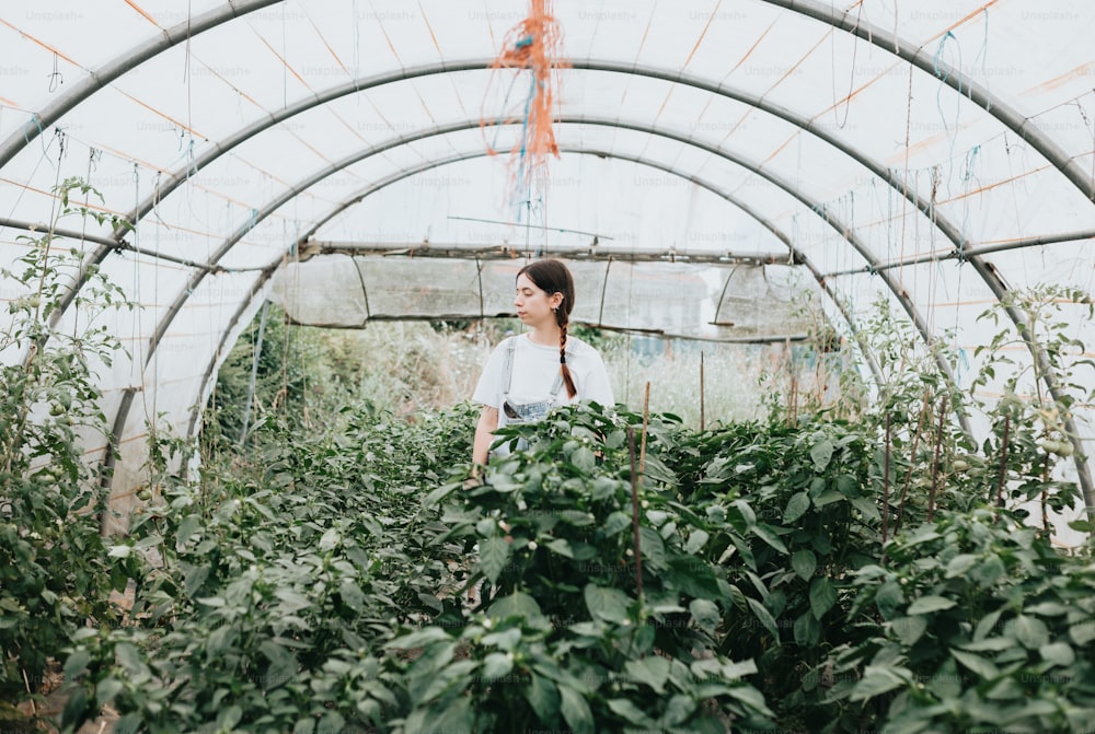 a woman standing in a greenhouse surrounded by plants