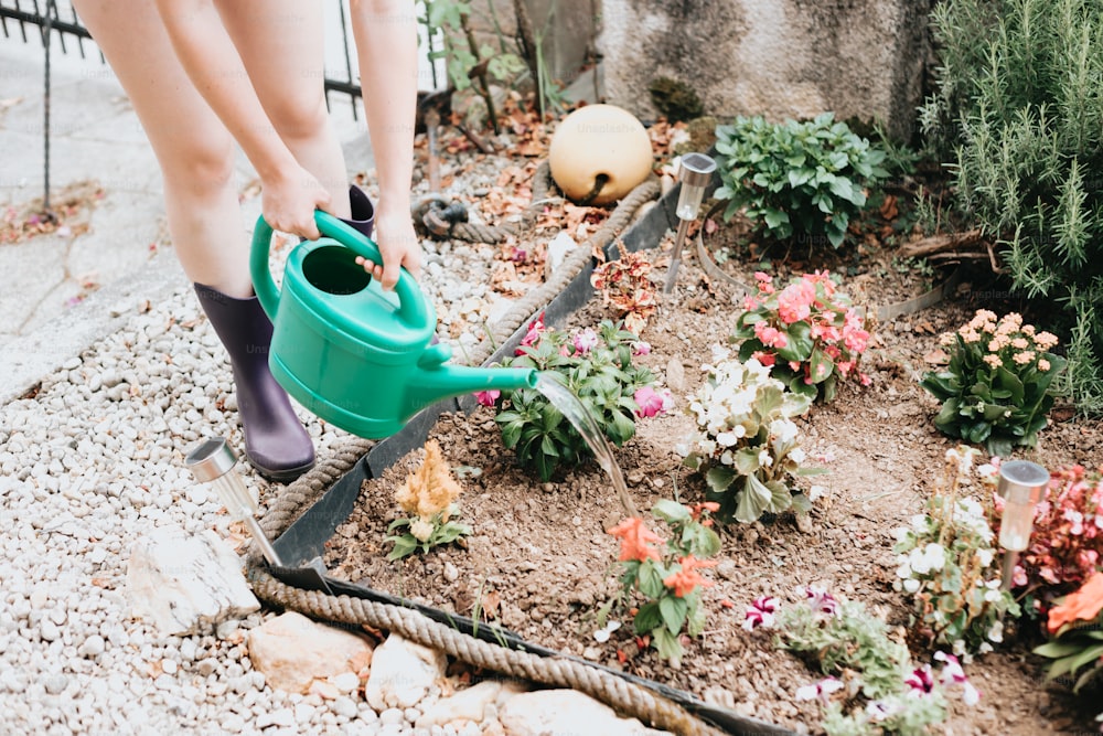 a woman is watering flowers in a garden