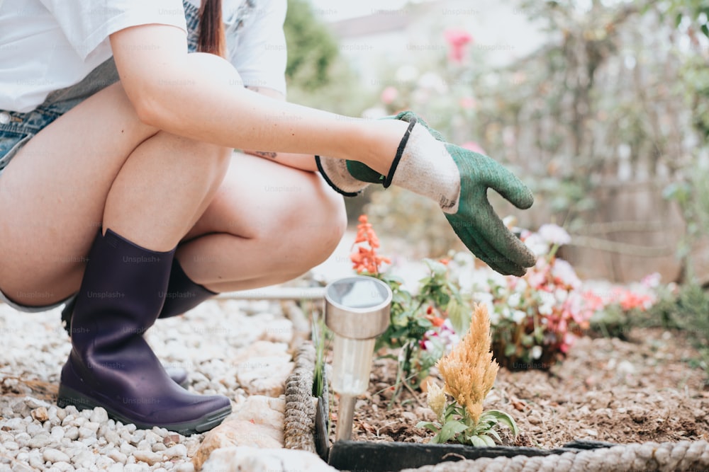 a woman kneeling down with gardening gloves on