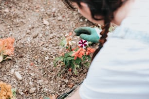 a woman in a white shirt is picking flowers