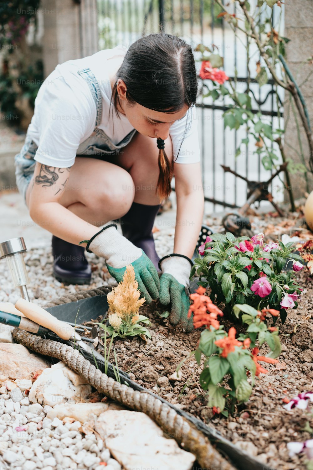 a woman kneeling down to plant flowers in a garden