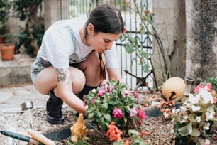 a woman kneeling down to plant flowers in a garden