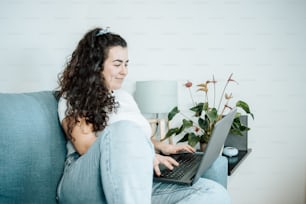 a woman sitting on a couch using a laptop computer