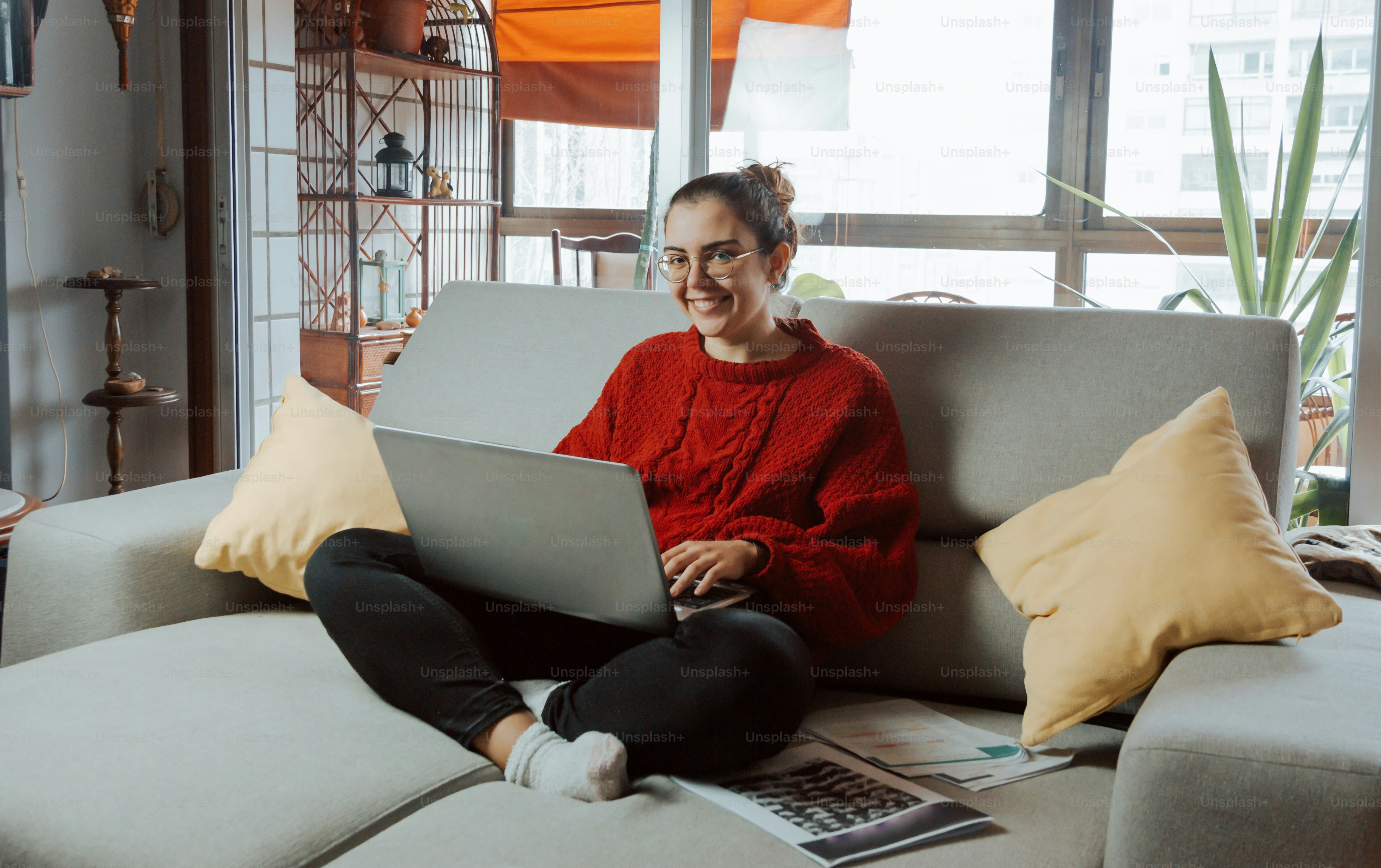 Una mujer sentada en un sofá usando una computadora portátil