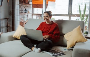 uma mulher sentada em um sofá usando um laptop
