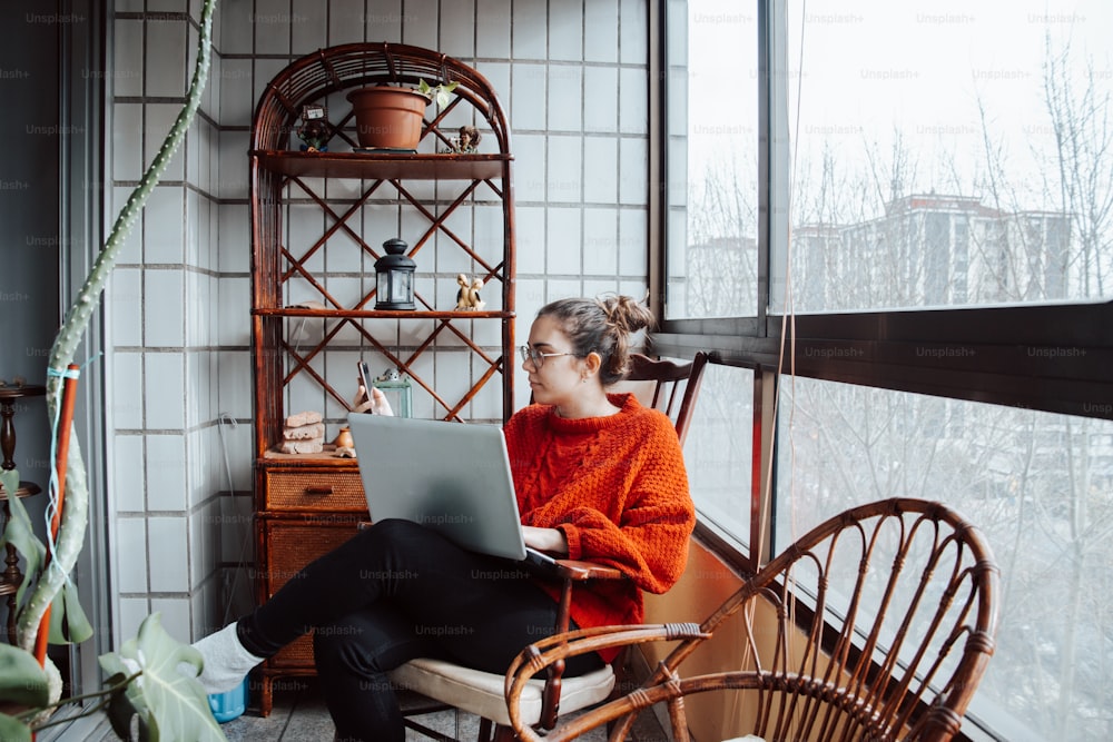 a woman sitting on a chair using a laptop computer