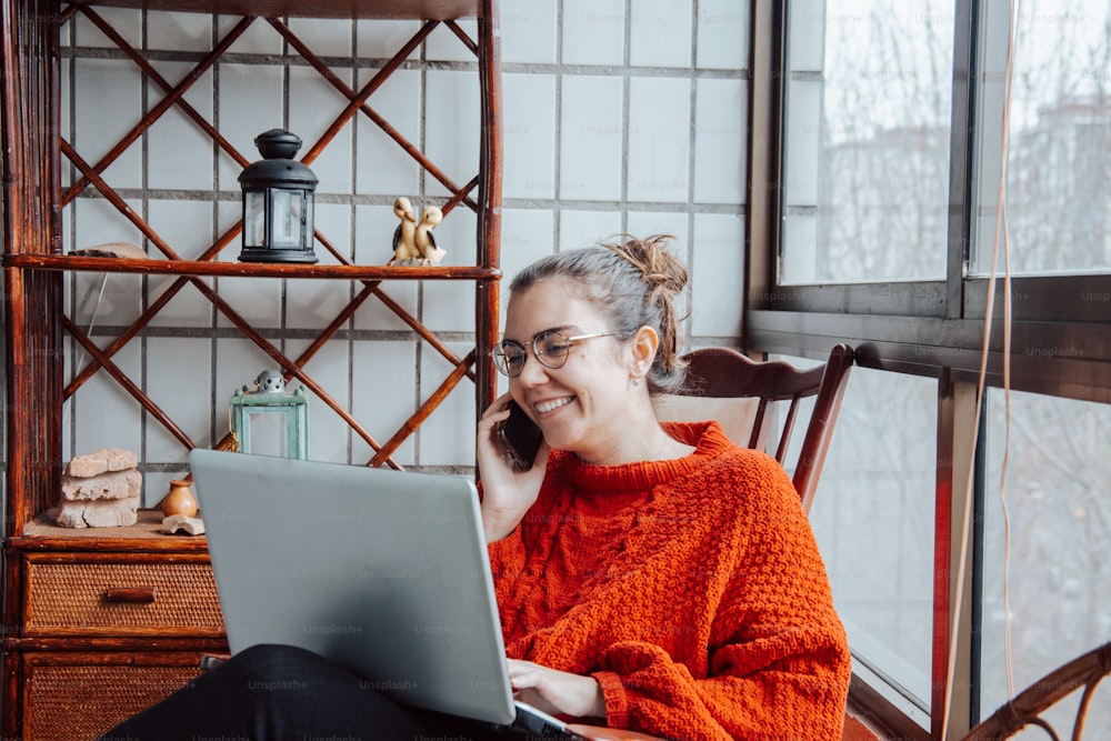 Una mujer sentada en una silla usando una computadora portátil