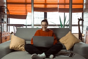 a woman sitting on a couch using a laptop