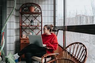 a woman sitting on a chair using a laptop computer