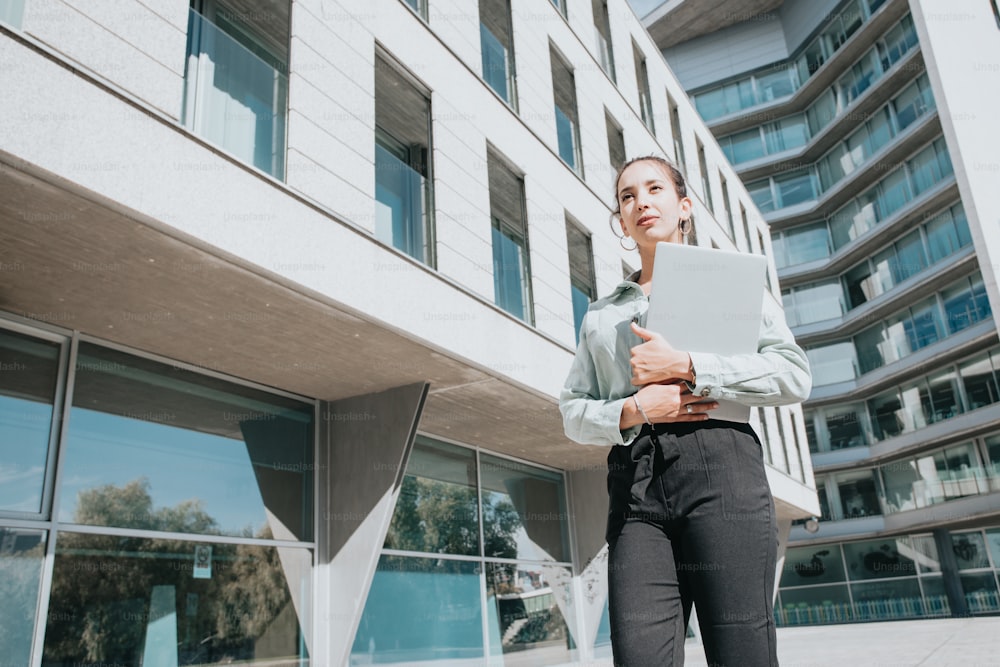 a woman standing outside of a building with a laptop