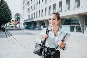 a woman holding a black bag and a tablet computer