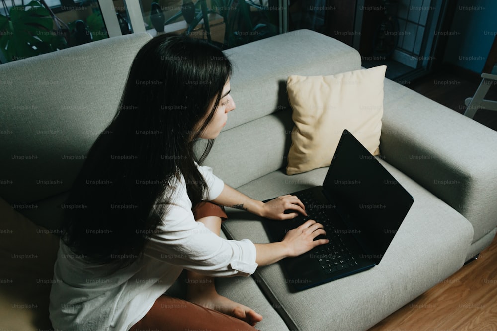 a woman sitting on a couch using a laptop computer