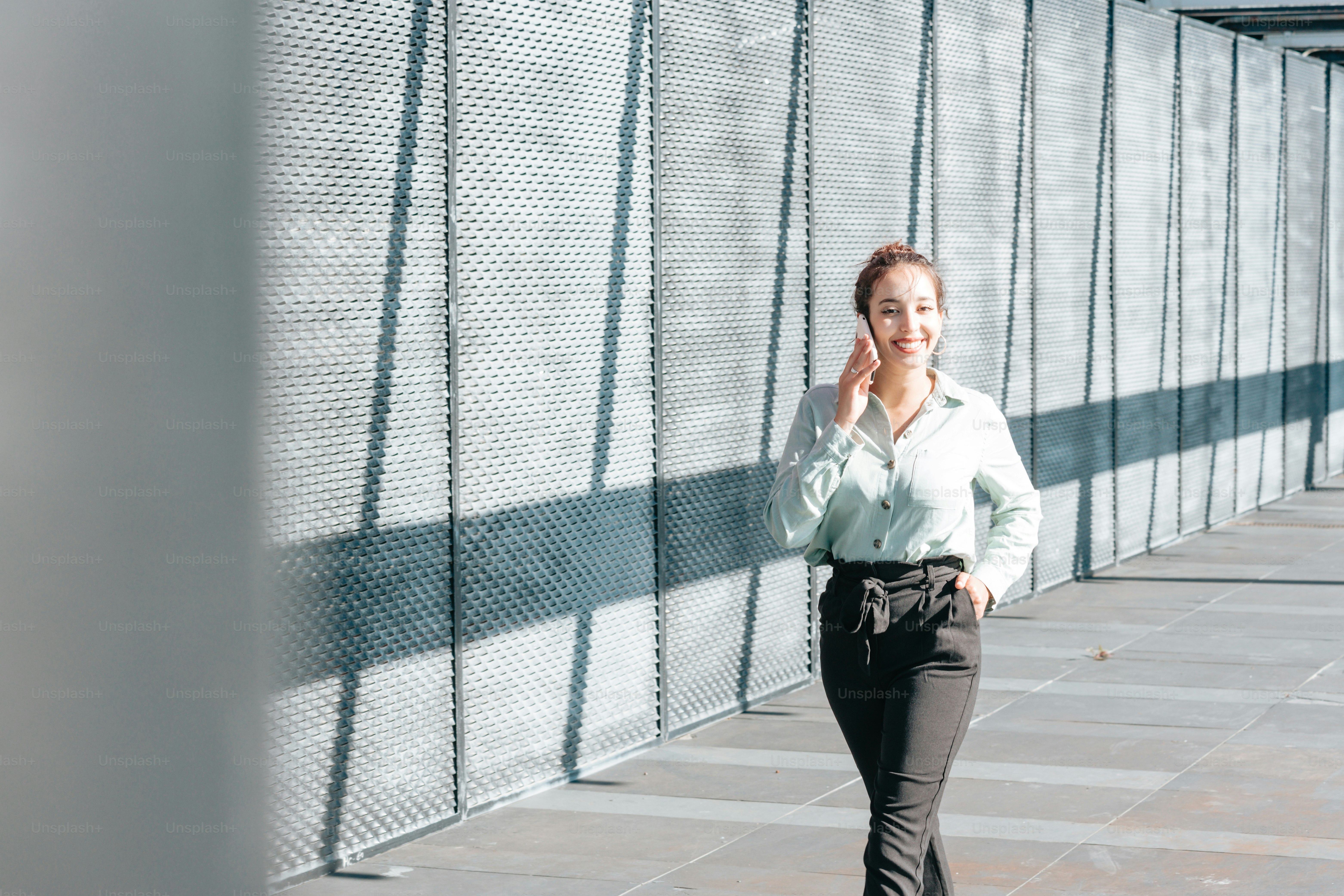 a woman walking down a sidewalk while talking on a cell phone