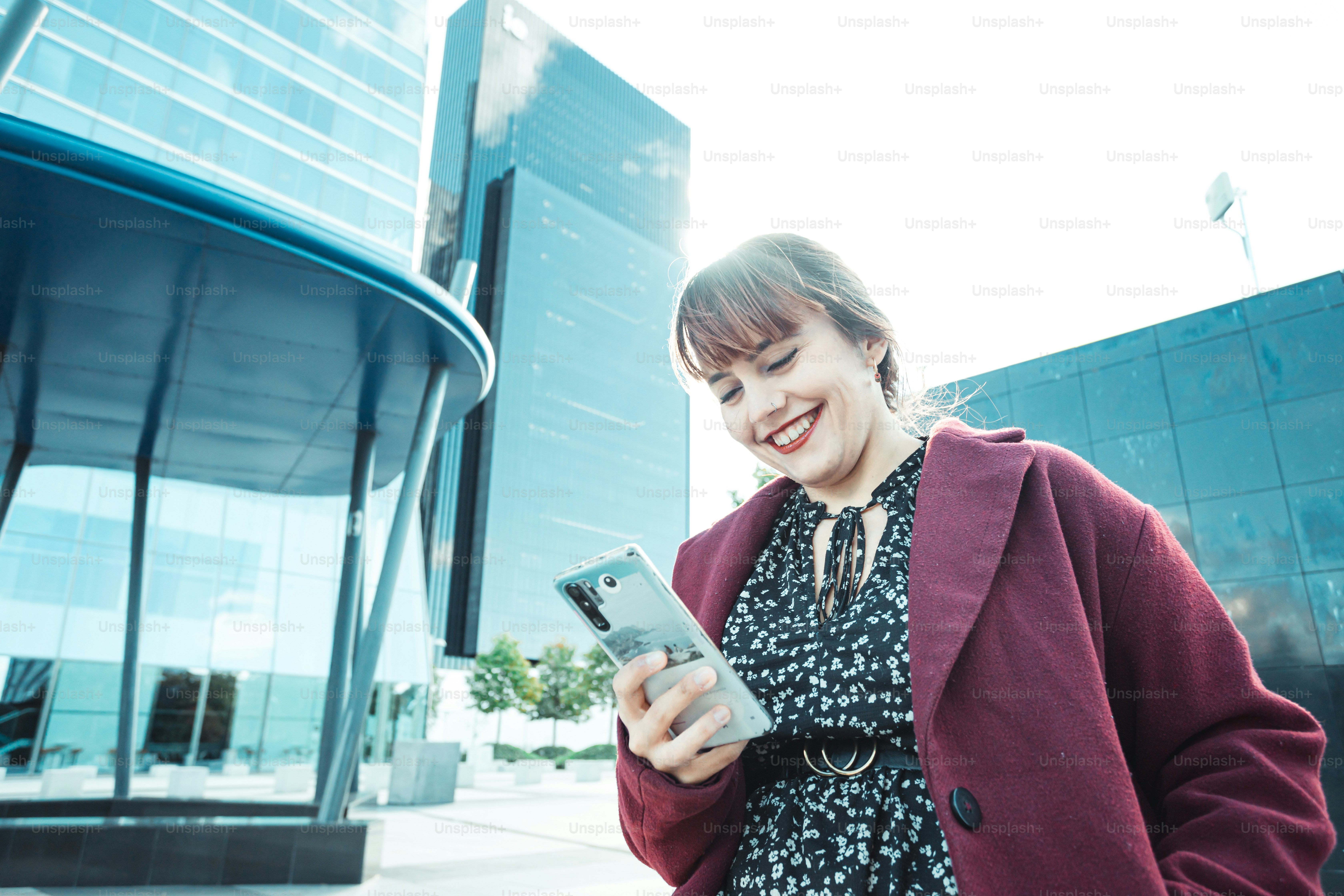 a woman is smiling while looking at her cell phone