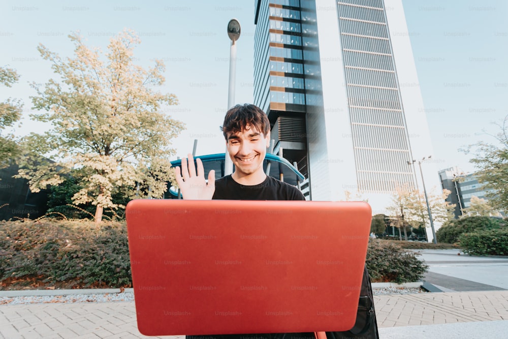 um homem segurando um laptop vermelho na frente de seu rosto