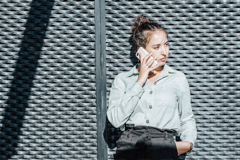 a woman talking on a cell phone while standing in front of a wall