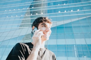 한 남자가 고층 빌딩 앞에서 휴대폰으로 통화하고 있다